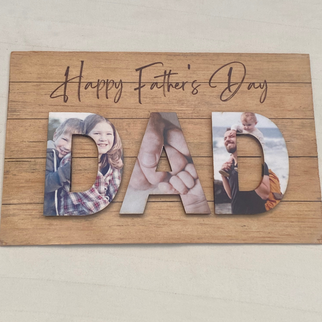 Wooden sign with 'Happy Father's Day' and photos of a family in the letters 'DAD'.