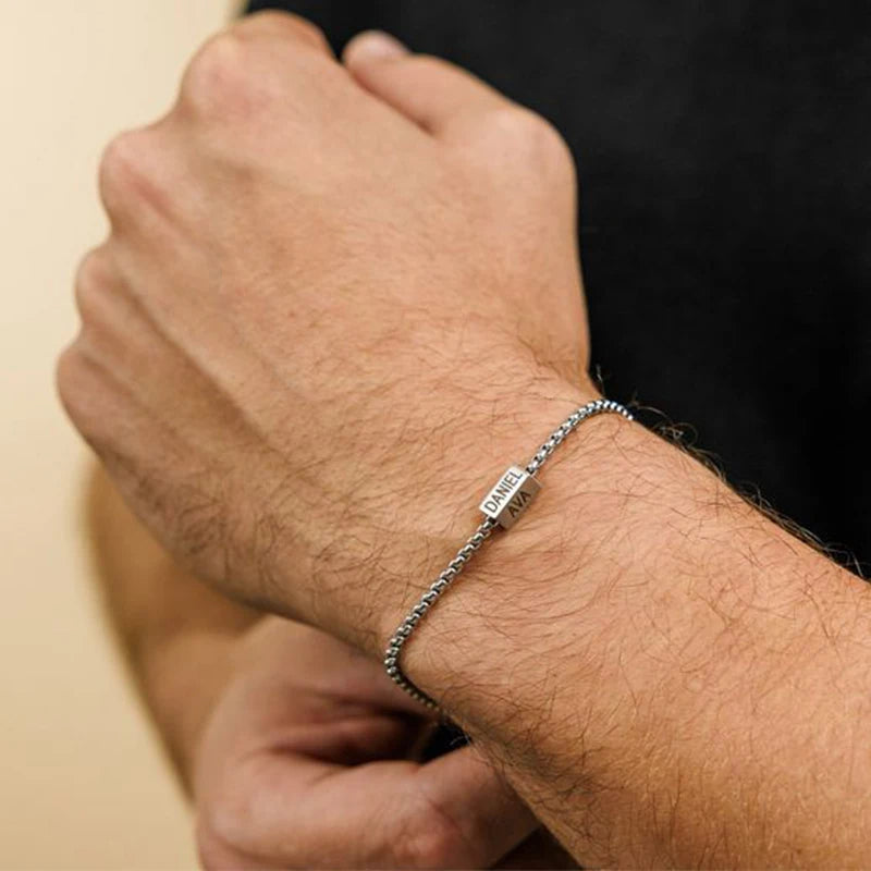 Close-up of a person's wrist wearing a silver bracelet with a blurred background