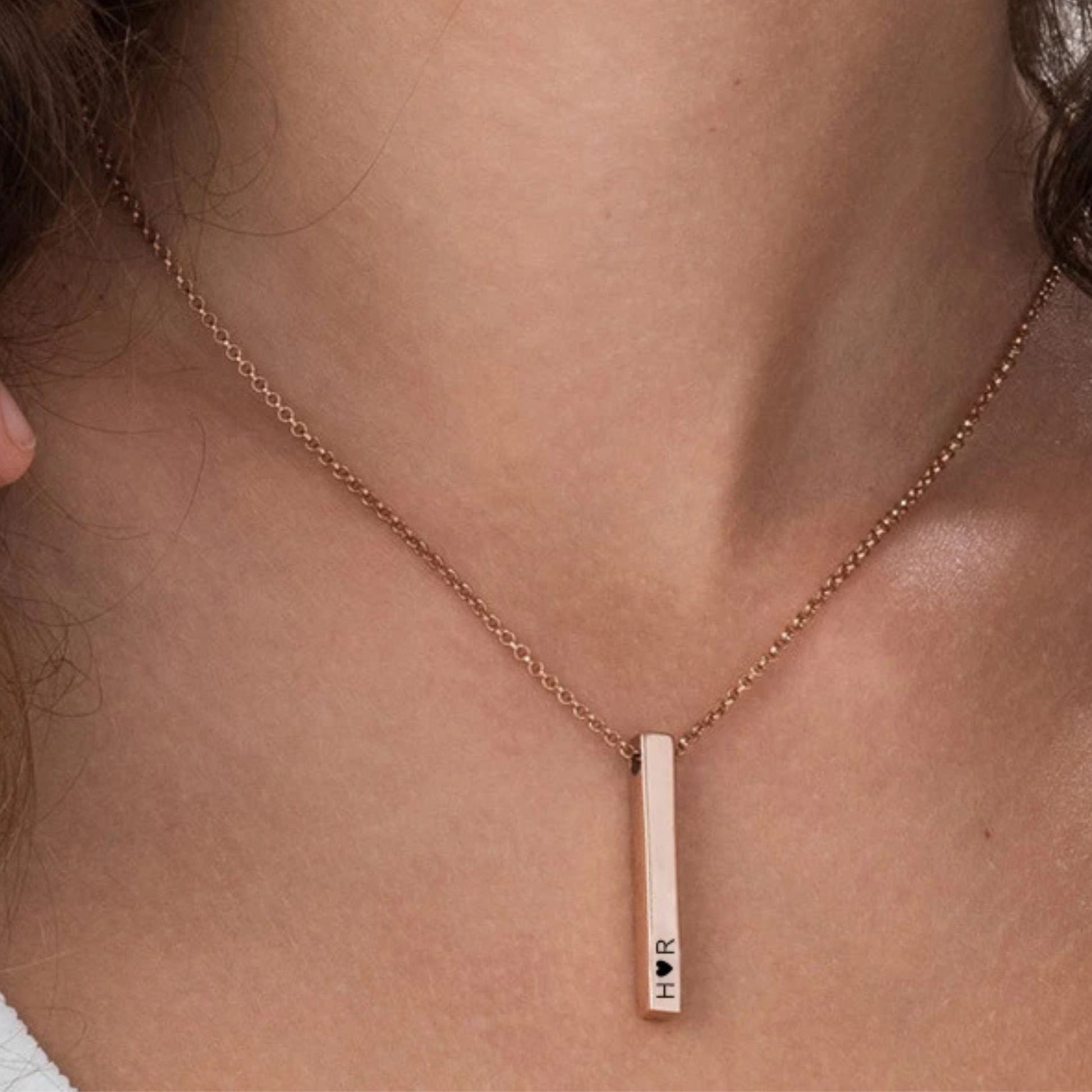 Rose gold necklace with a vertical bar pendant on a person's neck