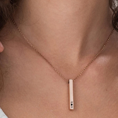 Rose gold necklace with a vertical bar pendant on a person's neck