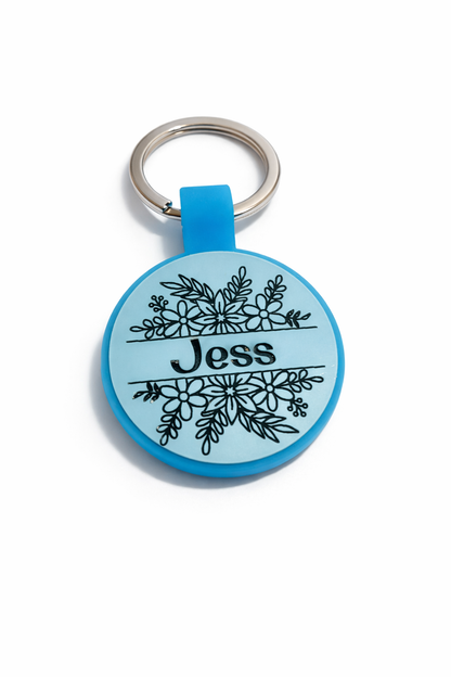 Blue pet name tag with floral design and 'Jess' text on a white background