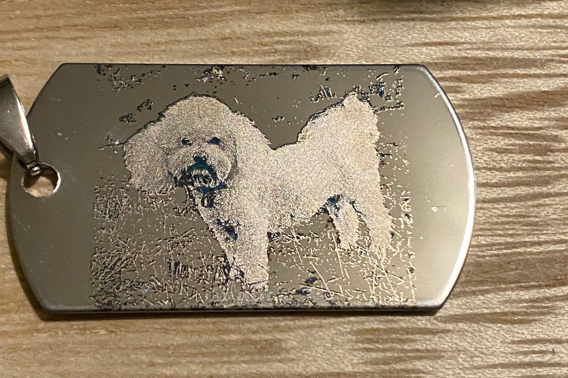 Metal dog tag with engraved design on a wooden surface
