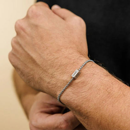 Close-up of a person's wrist wearing a silver bracelet with a blurred background