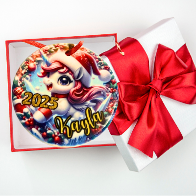 christmas ornament with unicorn design, '2025', and 'Kayla' text, wrapped in a gift box with a red bow.