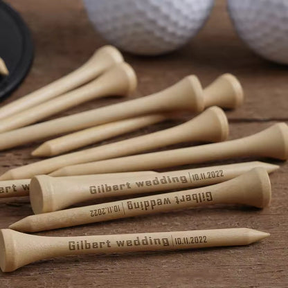 Personalized wooden golf tees with engraved text on a wooden surface with golf balls in the background.