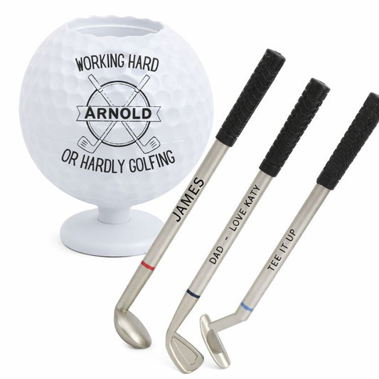 Golf ball with 'Working Hard Arnold or Hardly Golfing' text, and personalized golf clubs on a white background.
