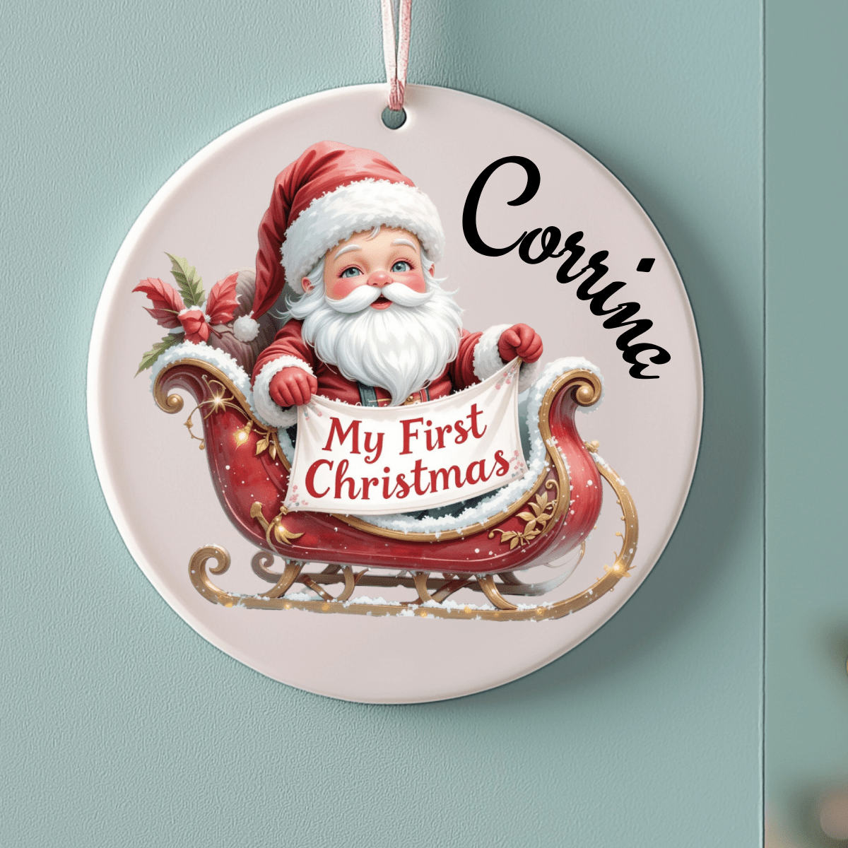 Decorative Christmas ornament with Santa Claus and 'My First Christmas' text on a light blue background.